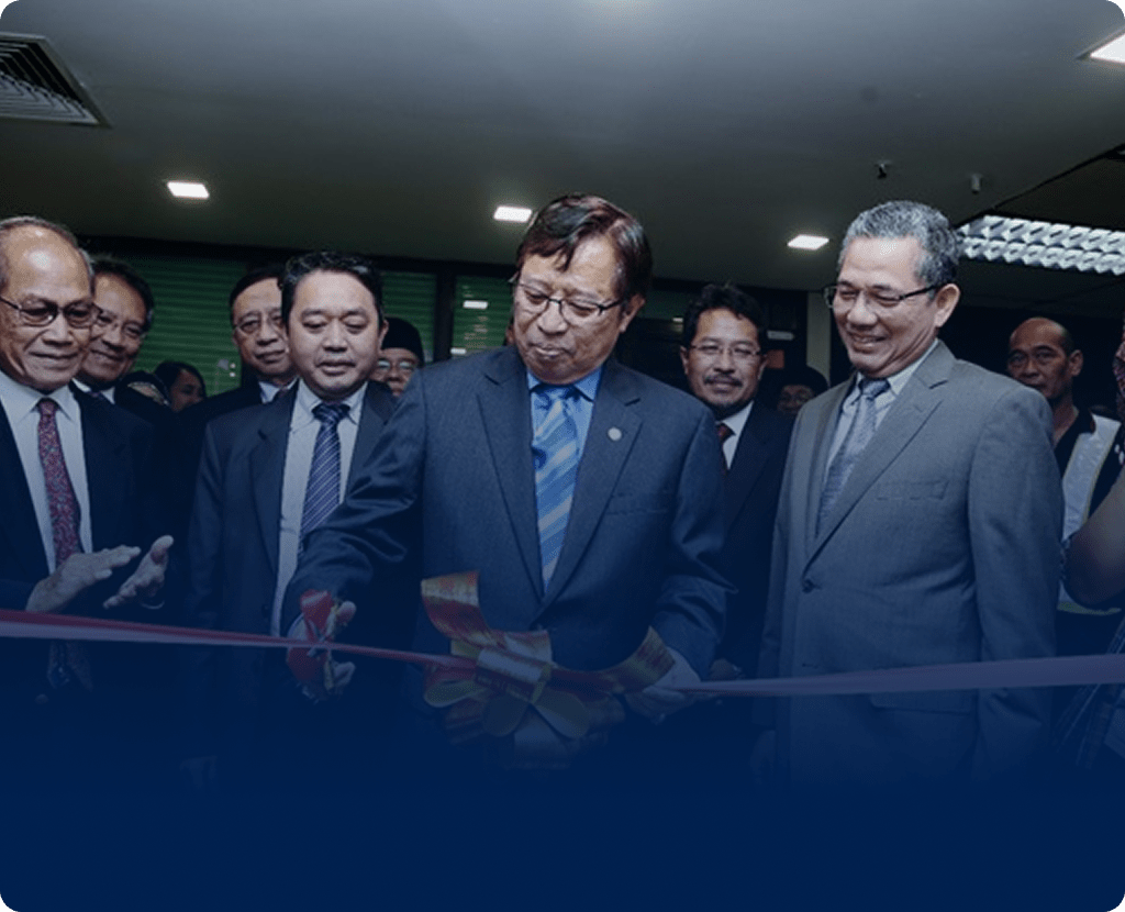 Man in suit cuts ribbon at formal opening ceremony.